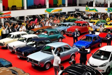 Uma cena vibrante de um leilão de carros no Brasil, com uma variedade de veículos, desde clássicos vintages até carros modernos econômicos, com licitantes entusiasmados e um leiloeiro em uma plataforma elevada.