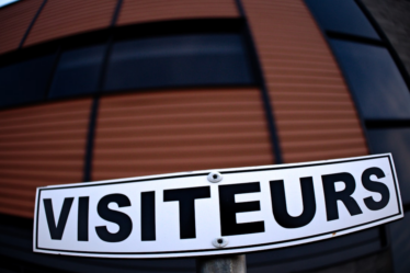 a white street sign sitting in front of a building — Foto por Danielle-Claude Bélanger na Unsplash