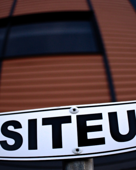 a white street sign sitting in front of a building — Foto por Danielle-Claude Bélanger na Unsplash