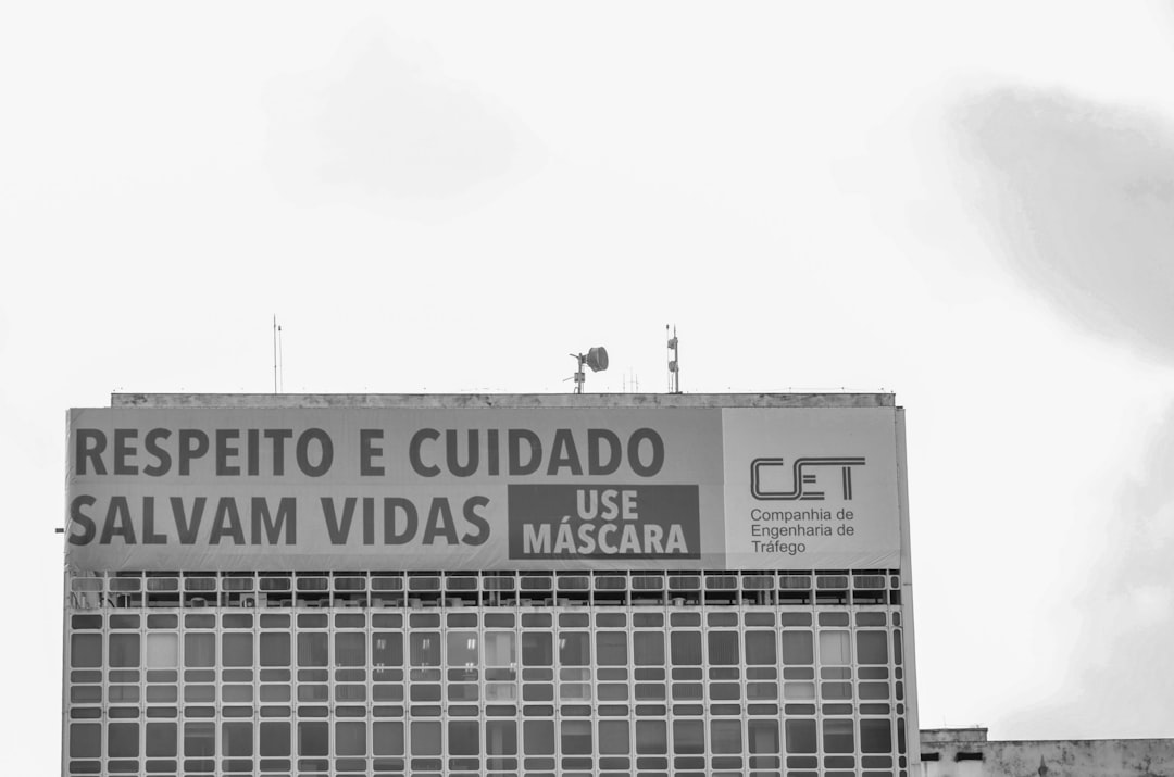 a tall building with a sign on the side of it — Foto por Anderson Menezes Da Silva na Unsplash