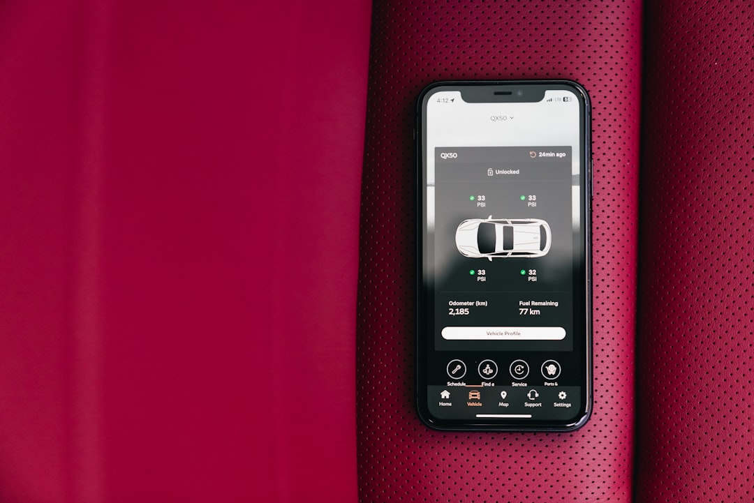 Smartphone displaying car control app on red seat — Foto por Erik Mclean na Unsplash