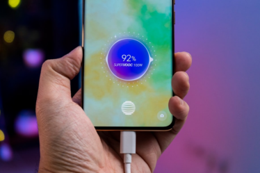 a person holding a cell phone with a charger in their hand — Foto por Amanz na Unsplash