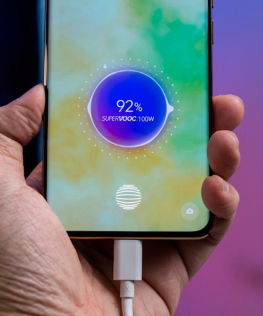 a person holding a cell phone with a charger in their hand — Foto por Amanz na Unsplash