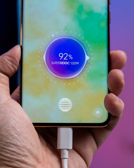a person holding a cell phone with a charger in their hand — Foto por Amanz na Unsplash