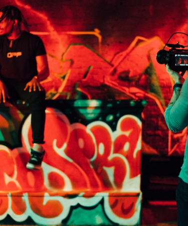 man in black and white crew neck t-shirt holding black dslr camera — Foto por Gordon Cowie na Unsplash