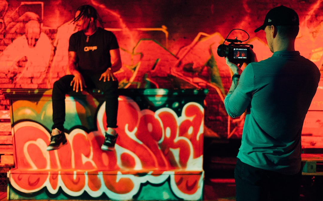 man in black and white crew neck t-shirt holding black dslr camera — Foto por Gordon Cowie na Unsplash