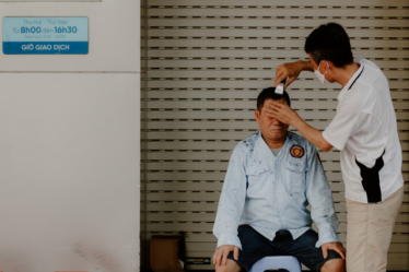 a man sitting on the floor with another man standing by him — Foto por Nam Hoang na Unsplash