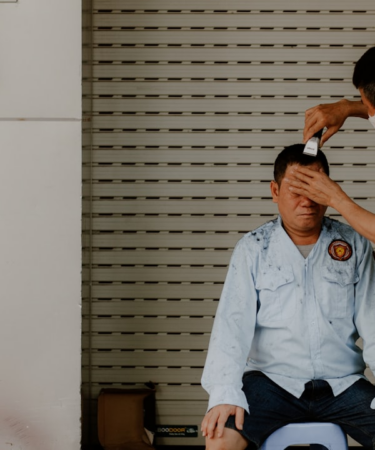 a man sitting on the floor with another man standing by him — Foto por Nam Hoang na Unsplash