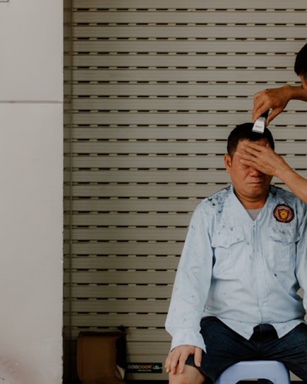 a man sitting on the floor with another man standing by him — Foto por Nam Hoang na Unsplash