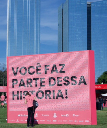 Large pink sign with portuguese text in a park. — Foto por Vinícius Costa na Unsplash