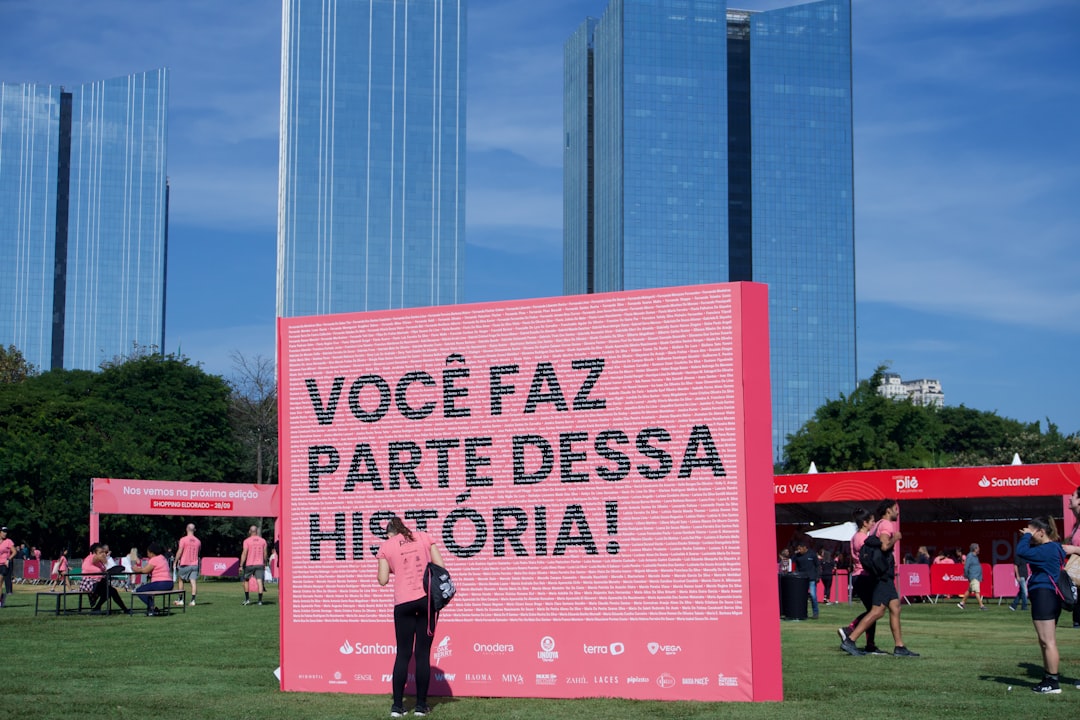 Large pink sign with portuguese text in a park. — Foto por Vinícius Costa na Unsplash