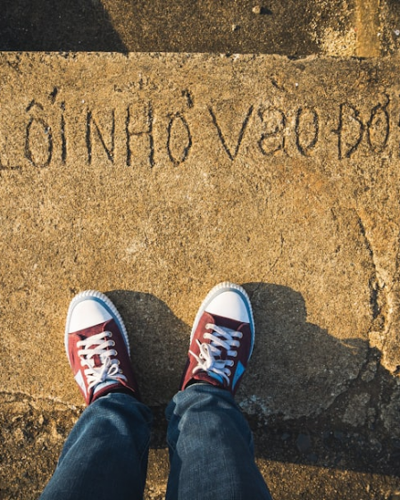 a person standing on a sidewalk with their feet up — Foto por Tien Vu Ngoc na Unsplash