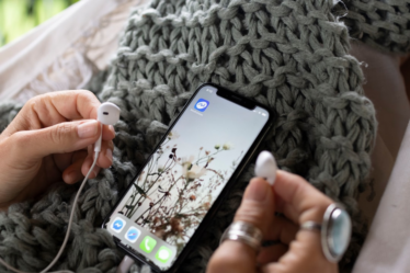 a person holding a cell phone and ear buds — Foto por Mindfulness Com na Unsplash