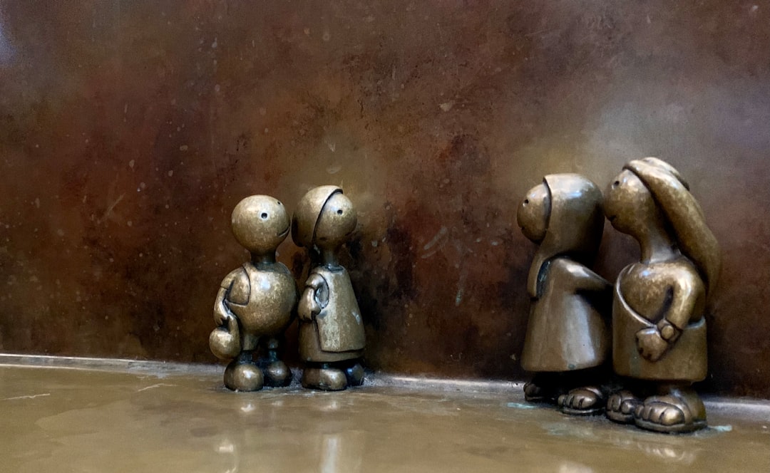 three metal figurines of people standing next to each other — Foto por Praveen Kumar Nandagiri na Unsplash