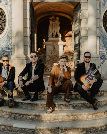 Four musicians posing on stone steps outside building — Foto por Lolla Woodstock na Unsplash