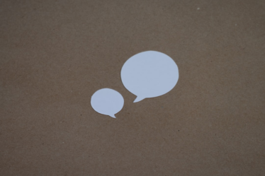two white speech bubbles sitting on top of a brown surface — Foto por Kelly Sikkema na Unsplash