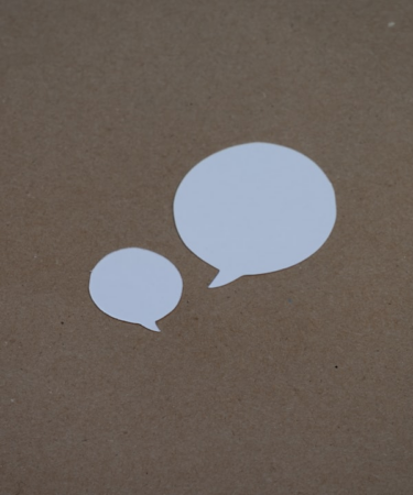 two white speech bubbles sitting on top of a brown surface — Foto por Kelly Sikkema na Unsplash