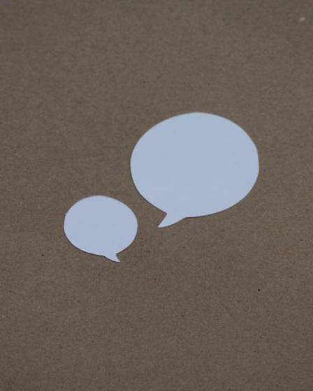 two white speech bubbles sitting on top of a brown surface — Foto por Kelly Sikkema na Unsplash