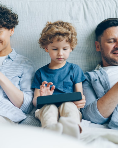 a man, woman and child sitting on a couch looking at their cell phones — Foto por Vitaly Gariev na Unsplash