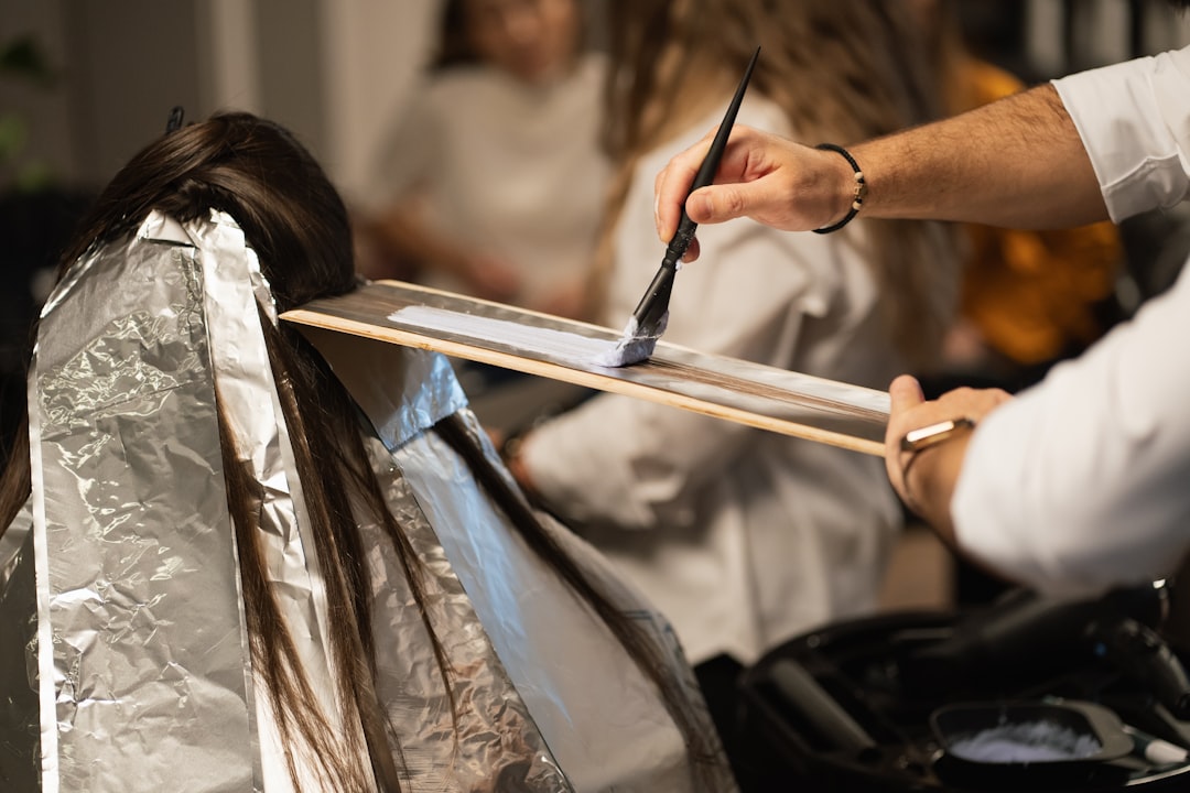 a man cutting a woman's hair with a pair of scissors — Foto por Ionela Mat na Unsplash