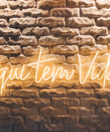 a brick wall with a neon sign on it — Foto por Antonino Visalli na Unsplash