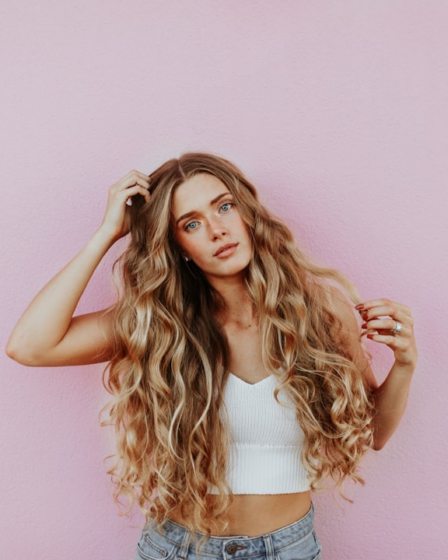 woman standing next to pink wall while scratching her head — Foto por averie woodard na Unsplash