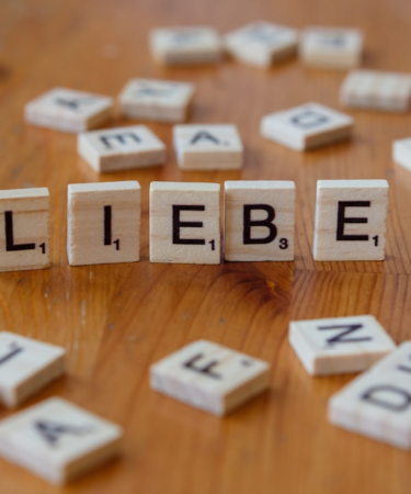 A wooden table topped with blocks that spell out the word liebe — Foto por Markus Winkler na Unsplash